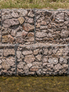 Strengthening the river bank with stones in a metal mesh